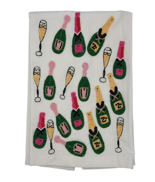 An off-white woven tea towel featuring a repeating pattern of green champagne bottles and champagne flutes decorated with colorful beadwork.